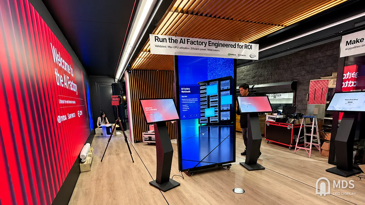 Wide view of the AI Factory Tour mobile exhibition with the MDS LED video wall, a central vertical LED display and interactive terminals