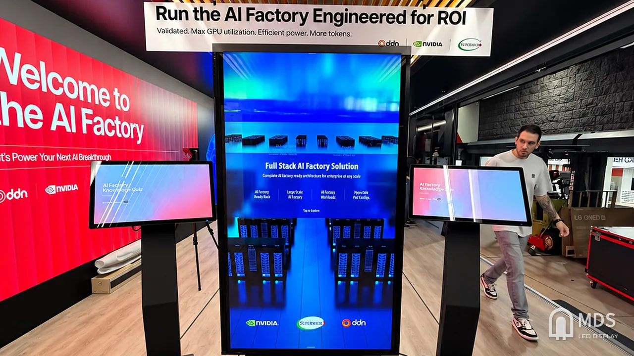 Front view of the central vertical MDS LED display between two interactive kiosks in the AI Factory Tour mobile exhibition
