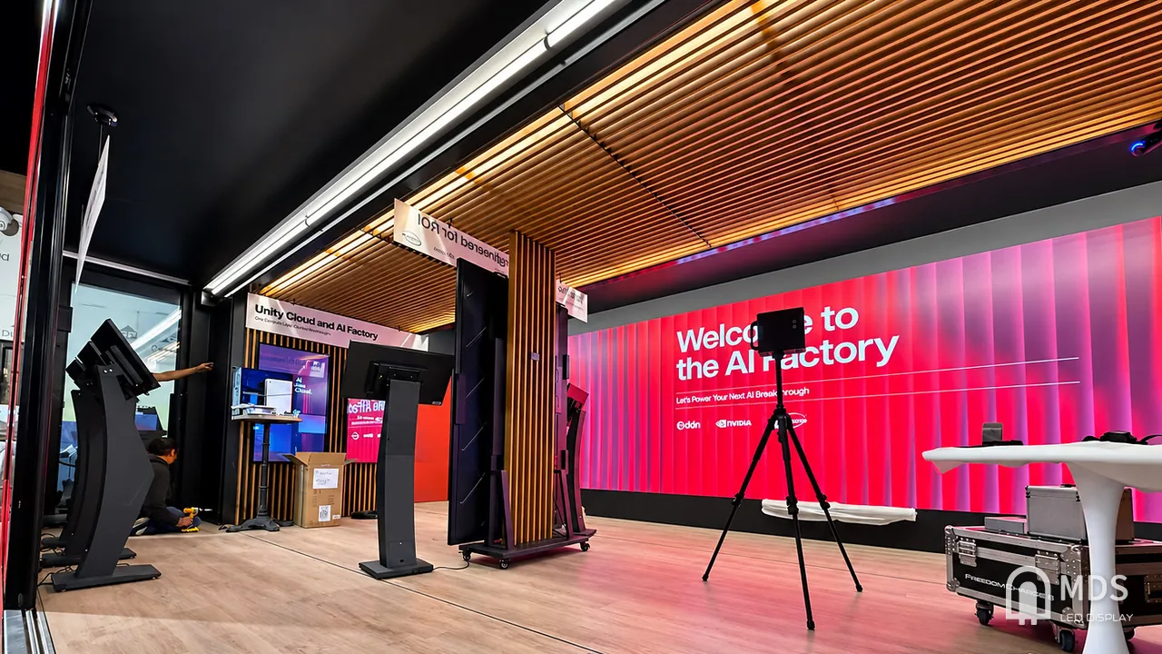 Inside the AI Factory Tour mobile exhibition trailer: MDS LED video wall across the side wall, vertical LED display and interactive kiosks being set up
