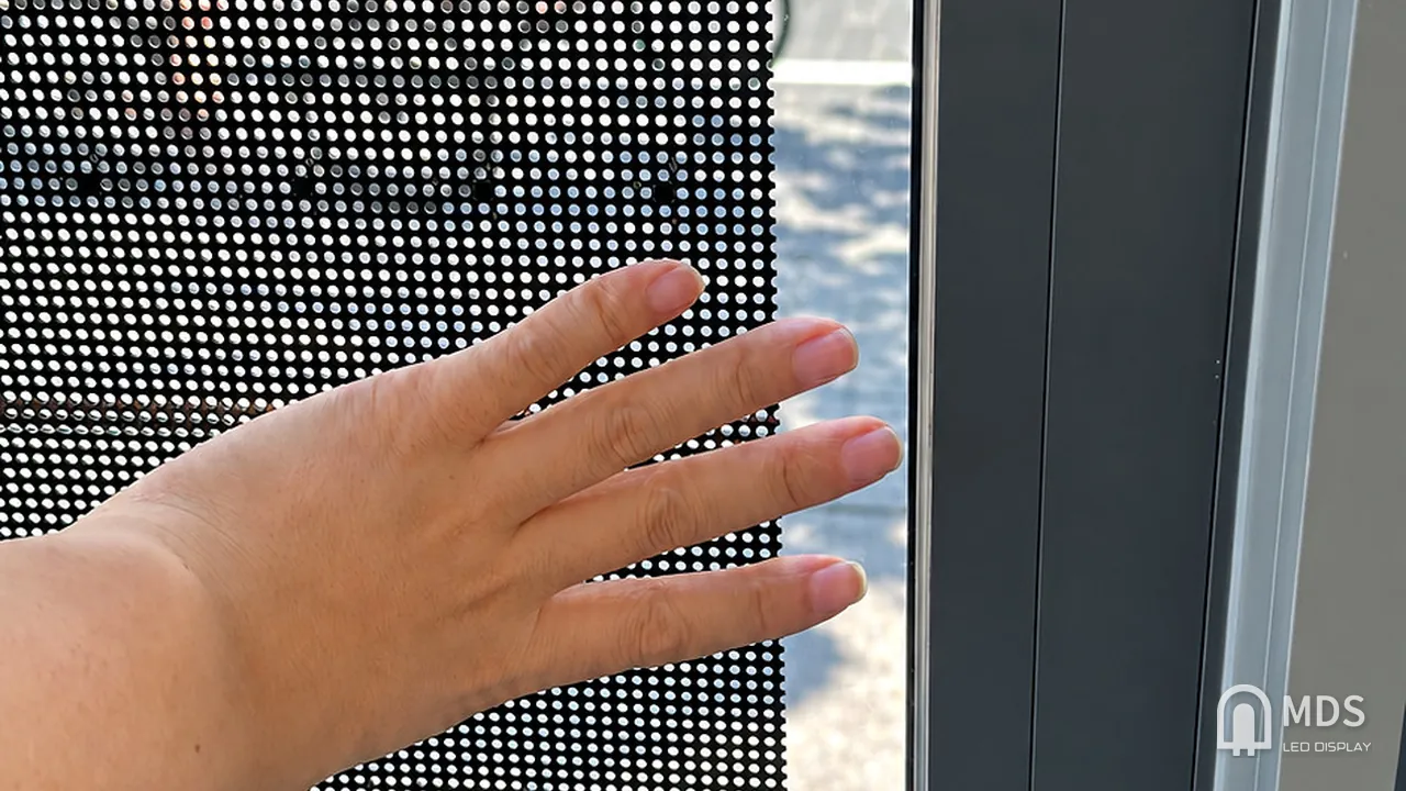 Close-up of the perforated mesh PCB on the MDS transparent LED window display, with the street visible through it, Vilnius